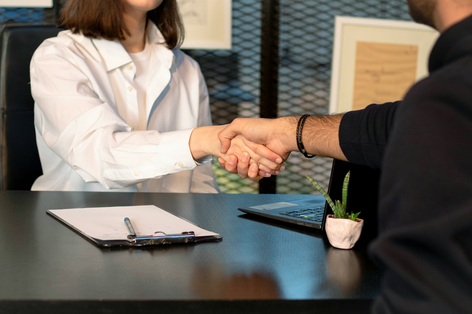 a man and a woman shaking hands in front of a laptop, surety bonds